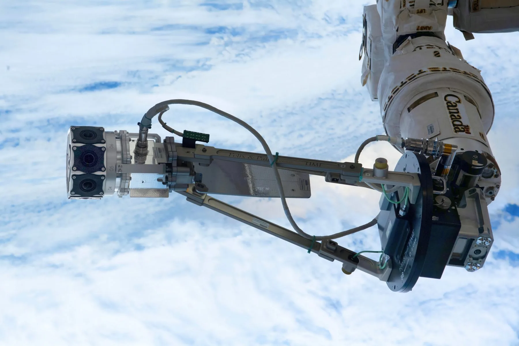 La caméra de sortie extravéhiculaire de Space Explorers sur le bras robotique, au-dessus de la Terre